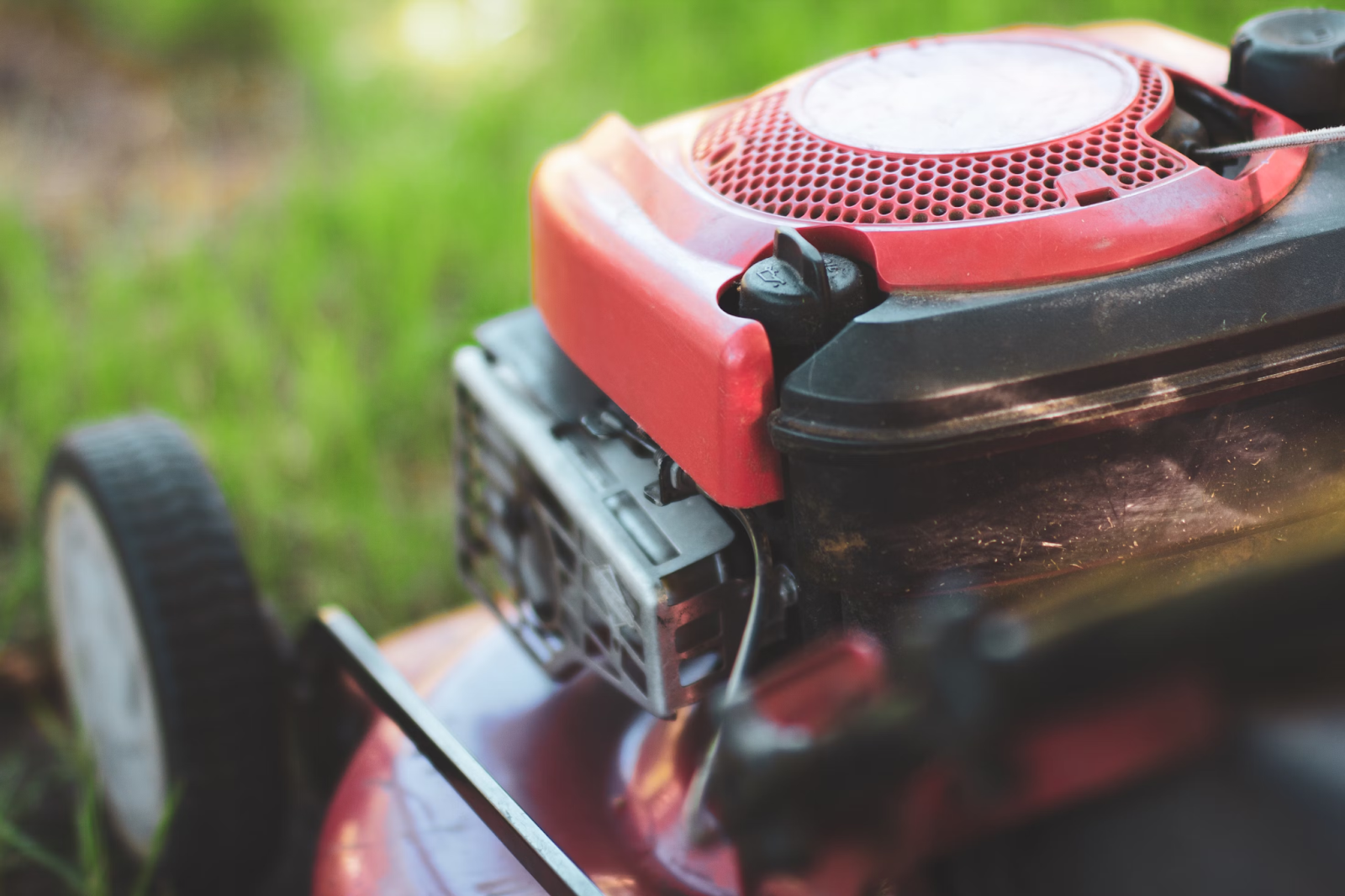 This image depicts an up-close view of a red push lawn mower. 