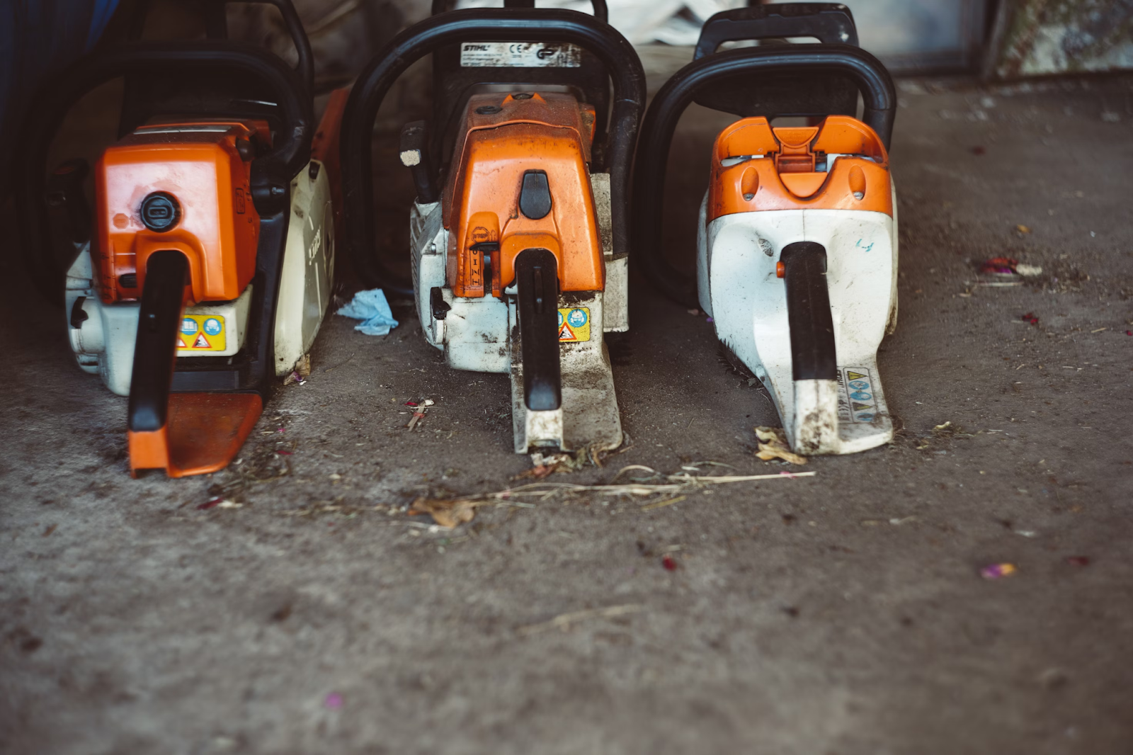 This image depicts three chainsaws set on the ground.