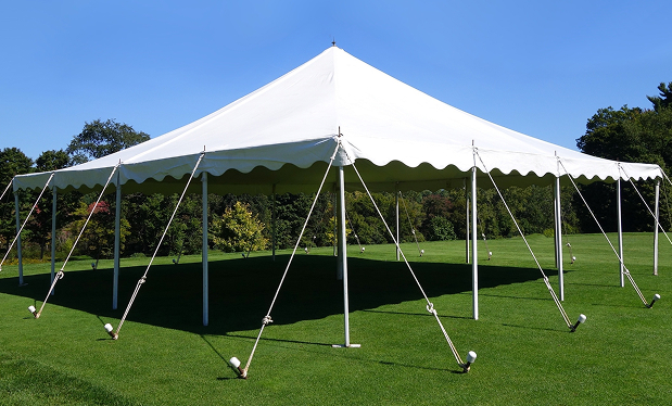 White outdoor tent set up on a grassy field under a clear blue sky.