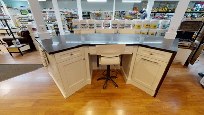 corner desk with black countertop, white cabinets, and a swivel chair in a store setting with wood flooring