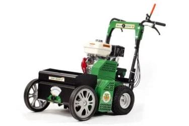 Green and black lawn aerator machine with wheels and handle, designed for aerating soil in gardening and landscaping.