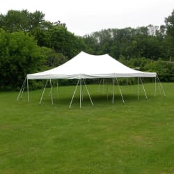 white event tent set up on a grassy field with trees in the background