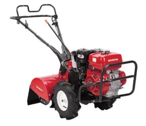 Red Honda tiller with two large black wheels, used for soil cultivation in gardens and landscaping tasks.