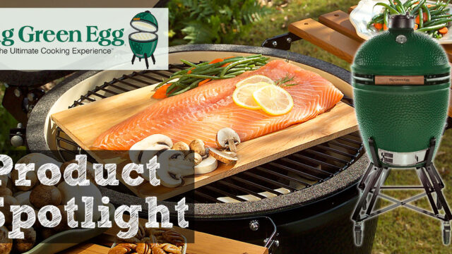 Salmon fillet on grill with lemon slices, mushrooms, and rosemary, outdoors with a Big Green Egg logo in the corner.