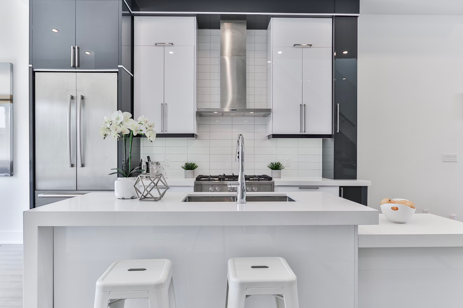 The picture depicts a white kitchen with a white marble countertop. The kitchen is modern with aesthetic cabinetry.