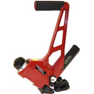 Red manual industrial strapping tool with black grip handle, used for securing packaging materials.