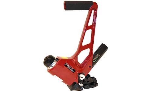 Red manual industrial strapping tool with black grip handle, used for securing packaging materials.