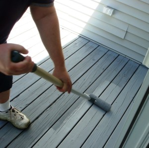 Man applying a coat of stain to his deck with a roller