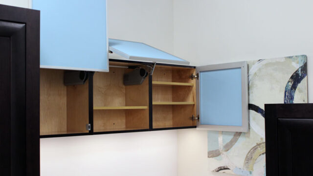 Open blue kitchen cabinets with empty wooden shelves and a modern light fixture above.