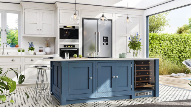Modern kitchen with blue island, stainless steel fridge, white cabinetry, pendant lights, and vase with flowers on countertop.