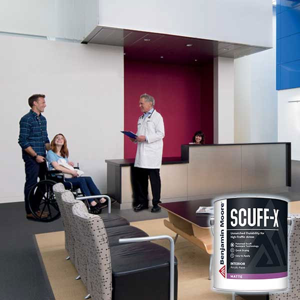 Doctor talking to a patient in a wheelchair and a visitor in a modern office waiting area with a paint can in the foreground.