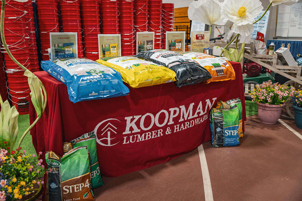 Display of various soil and garden products on a red tablecloth at Koopman Lumber & Hardware store event.